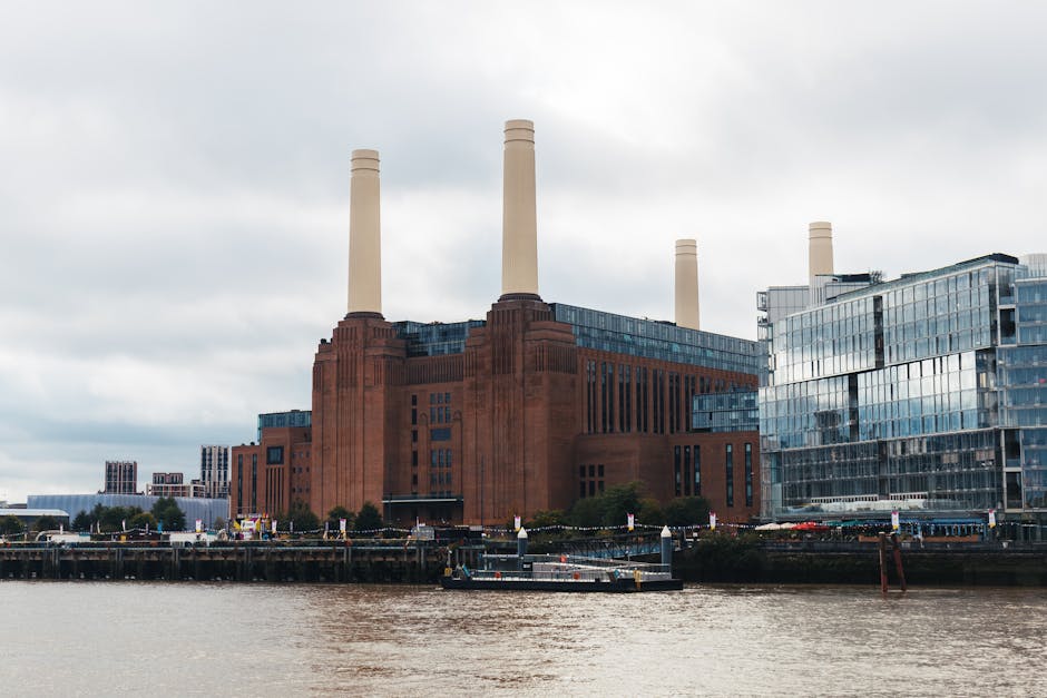 This image showcases a garden scene adjacent to the River Thames with a focus on outdoor maintenance. In the foreground, there are well-maintained grass lawns with a textured, trimmed surface, bordere